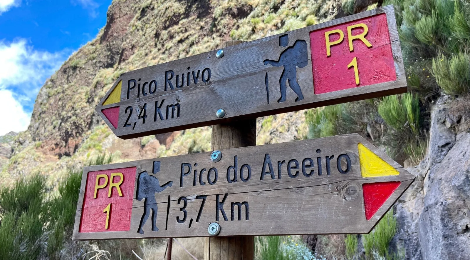Wooden PR1 trail signpost reading Pico Ruivo 2,4 km in one direction and Pico do Areeiro 3,7 km in the other